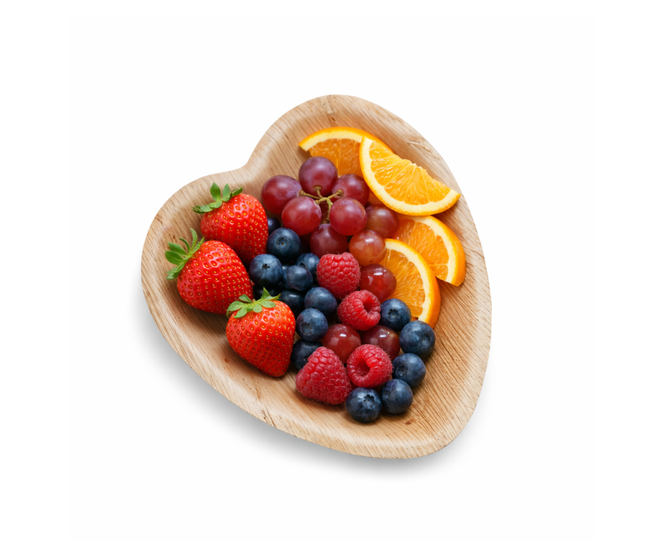 Heart-shaped palm leaf plate with fresh fruits on white background, sustainable disposable tableware