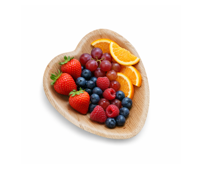 Heart-shaped palm leaf plate with fresh fruits on white background, sustainable disposable tableware